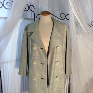 May include: A light blue double-breasted coat with a textured weave. The coat has a classic collar and is displayed on a mannequin.