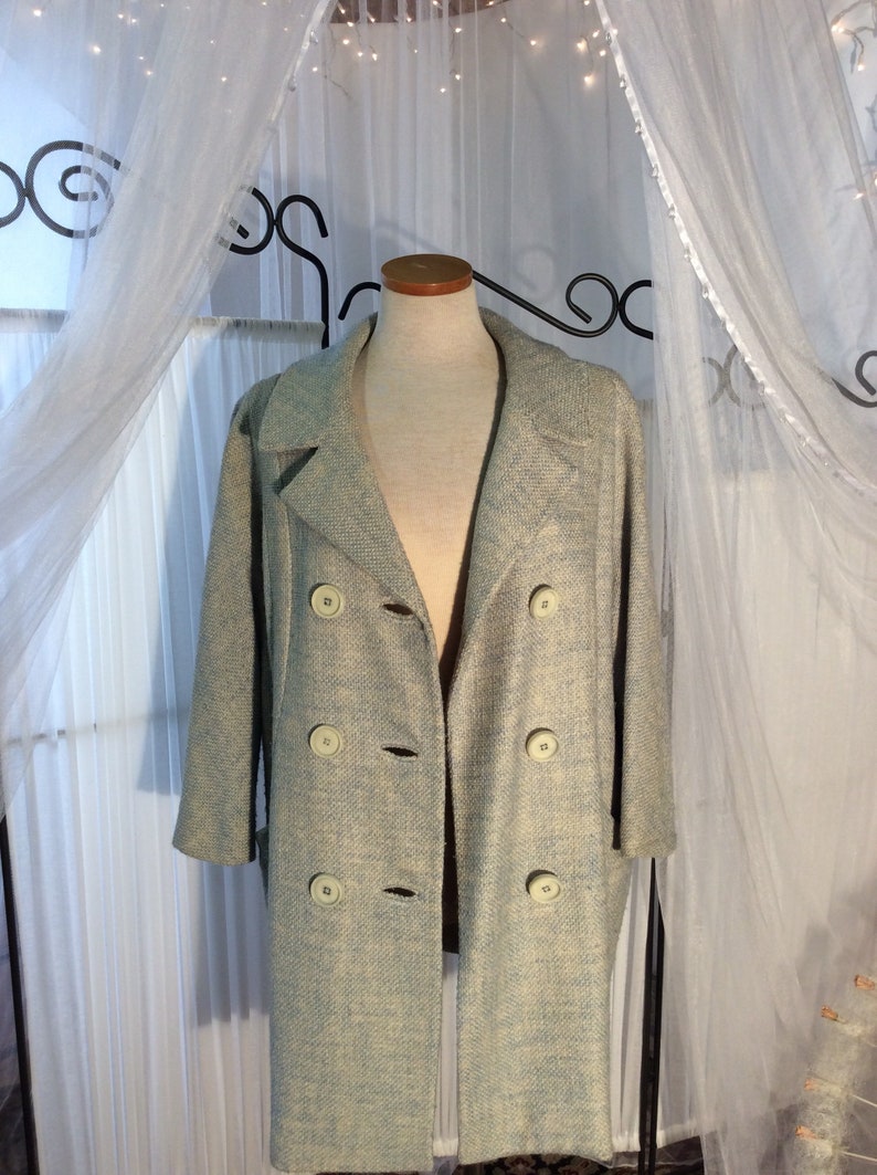 May include: A light blue double-breasted coat with a textured weave. The coat has a classic collar and is displayed on a mannequin.