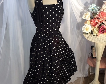May include: A black and white polka dot halter dress with a fitted bodice and a full skirt. The dress is sleeveless and has a halter neckline.