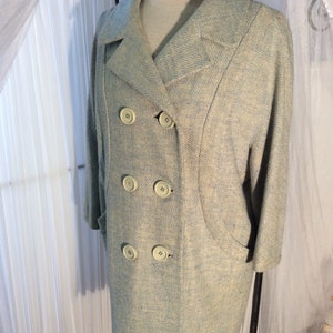 May include: A light blue double-breasted coat with a textured fabric and five large buttons.