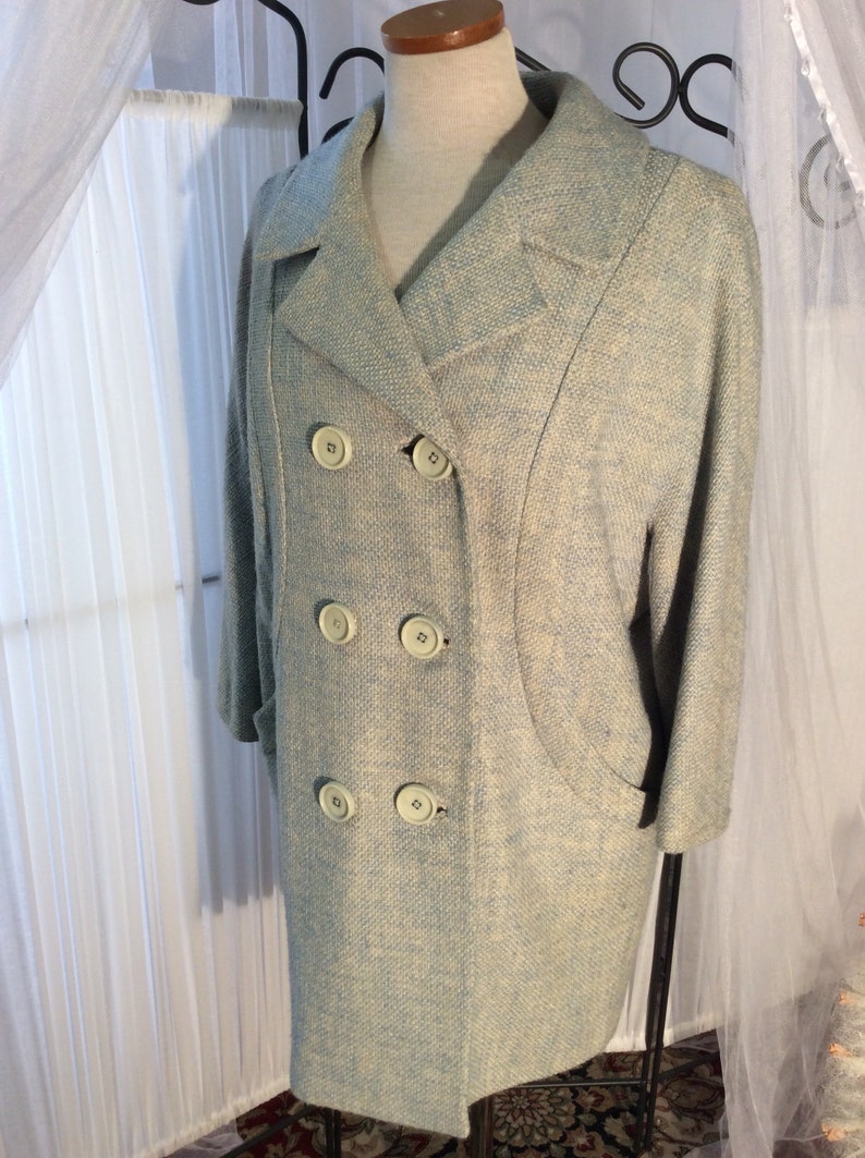 May include: A light blue double-breasted coat with a textured fabric and five large buttons.