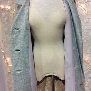 May include: A light blue blazer with a textured weave and a light gray lining. The blazer has a single button closure and two pockets.