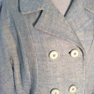 May include: A light blue blazer with a white and light blue patterned design. The blazer has a double breasted closure with four white buttons.