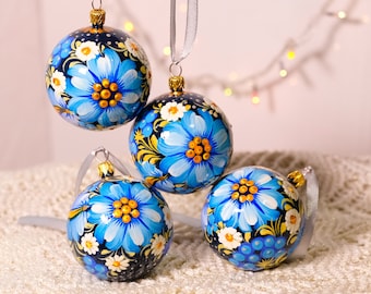 May include: Four hand-painted Christmas ornaments with blue and gold floral designs on a black background.