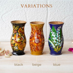 May include: Three wooden vases with hand-painted floral designs. The vases are in black, beige, and blue.