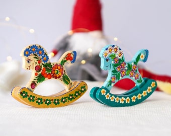 May include: Two wooden rocking horses painted with colorful floral designs. One horse is white with red, yellow, and blue flowers, and the other is blue with white and yellow flowers.
