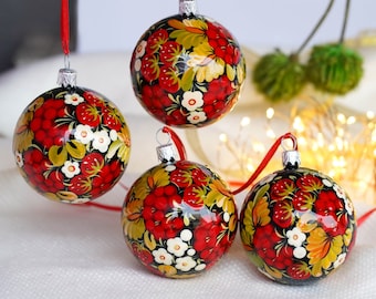 May include: Four hand-painted Christmas ornaments with a red, white, and black floral design. The ornaments are round and have a glossy finish.
