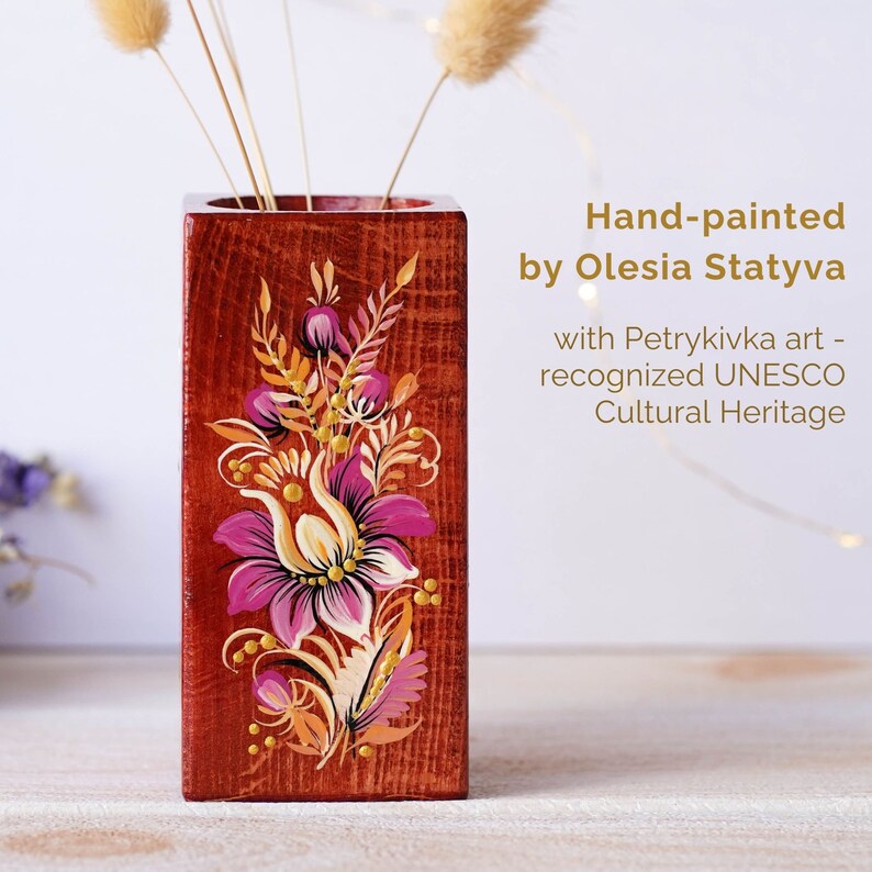Puede incluir: Jarr&oacute;n de madera pintado a mano con un dise&ntilde;o floral en tonos rosa, naranja y amarillo. El jarr&oacute;n est&aacute; decorado con el estilo tradicional del arte popular ucraniano, Petrykivka, reconocido por la UNESCO como Patrimonio Cultural.