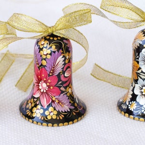May include: Three black bells with gold ribbon bows. Each bell is hand-painted with colorful floral designs. The bells are a traditional Russian folk art.