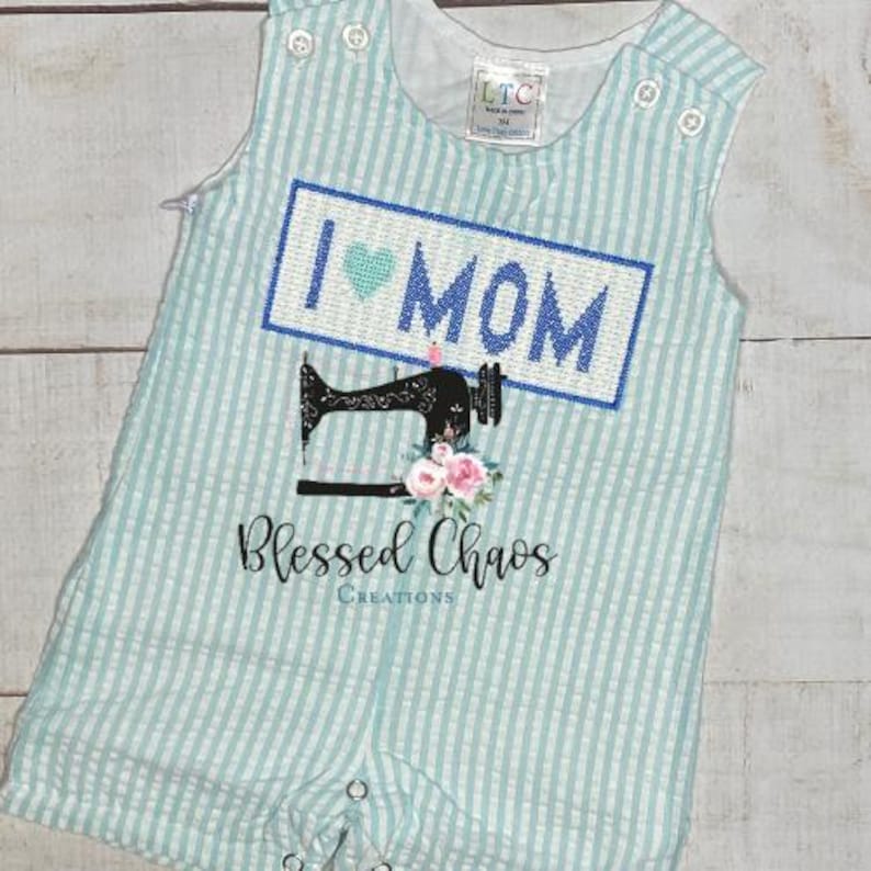 May include: A light blue and white striped baby onesie with a blue and white embroidered patch that says "I love Mom" with a heart. Below the patch is a black and white sewing machine with pink flowers. The onesie has a white text that says "Blessed Chaos Creations".