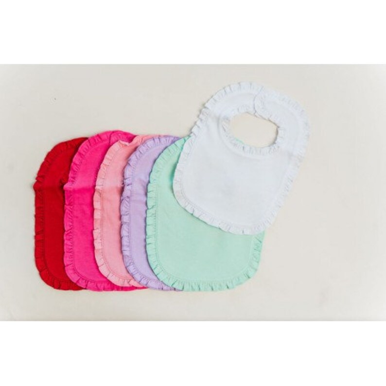 May include: Set of seven baby bibs with ruffled edges in various colors, including red, pink, light pink, lavender, light green, and white.
