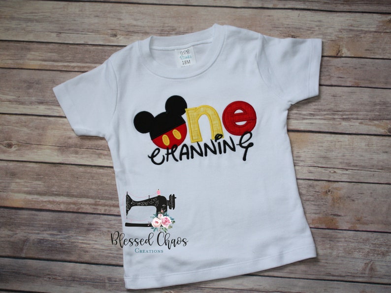 Peut inclure: T-shirt &agrave; manches courtes blanche avec un motif Mickey Mouse brod&eacute; en rouge, jaune et noir et le texte "one cranning".