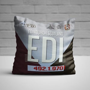 May include: A decorative pillow with the text "EDINBURGH.SCOTLAND EDI" in large white letters. The pillow has a color scheme of white, burgundy, and brown. The pillow also has the numbers "492.1.970" in red.