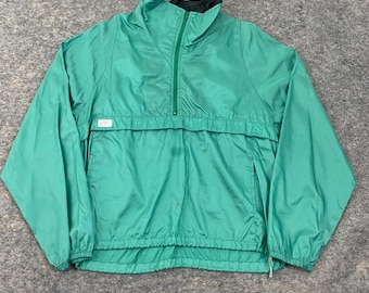 May include: A teal-colored anorak jacket with a half-zip closure and a high collar. The jacket features a front pocket and a small white tag. The cuffs and hem are elasticized. The interior collar is black.