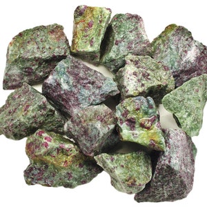 May include: A collection of rough, uncut ruby in zoisite stones. The stones are a mix of green and gray with vibrant red ruby inclusions. The natural gemstones are displayed against a white background, showcasing their raw beauty.