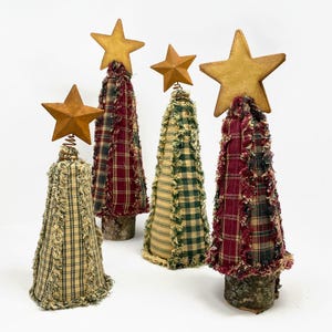 May include: Four handmade fabric Christmas trees with a plaid design and frayed edges. Each tree has a rustic wooden base and a star-shaped topper.