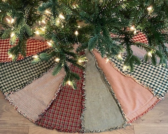 Puede incluir: Una falda de árbol de Navidad de patchwork con un borde deshilachado. La falda está hecha de tela de cuadros rojos, verdes y blancos.