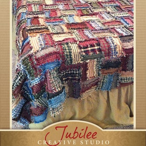 May include: A handmade rag quilt throw with a patchwork design in shades of red, blue, green, and brown. The quilt is made from repurposed fabric scraps and has a frayed edge. The quilt is displayed on a bed with a white bed skirt.