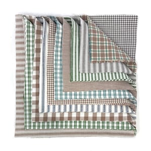 May include: A collection of fabric squares in a variety of patterns. The fabrics display stripes, checks, and plaid designs in shades of brown, green, white, and blue. The arrangement highlights the different textures and colour combinations.