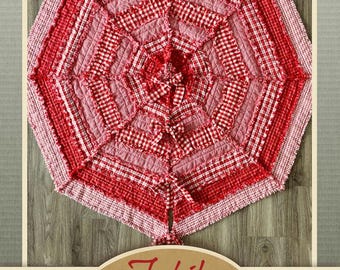 May include: A red and pink gingham Christmas tree skirt with a ruffled edge. The skirt is made from fabric scraps and has a patchwork design. The text "Tis the Season Christmas Tree Skirt Pattern" is printed at the bottom of the image.