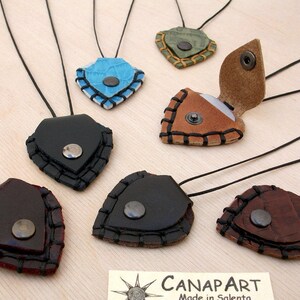 May include: Seven leather necklaces with a variety of colors and designs. Each necklace features a small, heart-shaped pendant with a metal button closure. The pendants are made of leather and have a stitched edge.