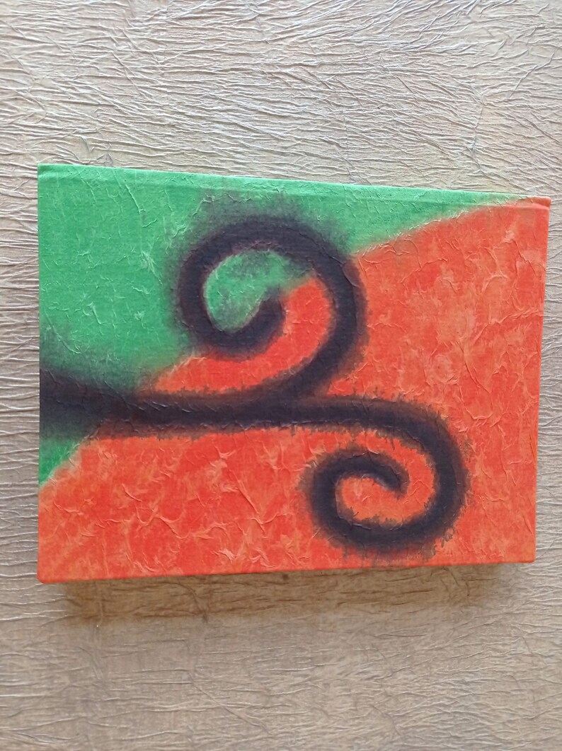 May include: A handmade journal with a textured cover featuring a black abstract design on a green and orange background.