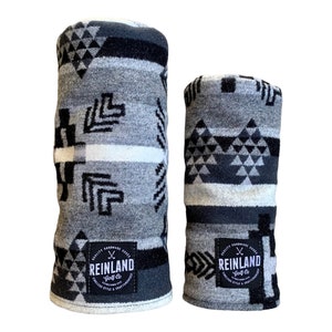 May include: Two gray and black patterned golf club head covers with a white stripe and a black and white logo that says "Reinland Golf Co.  Quality Handmade Goods. Timeless Style & Craftsmanship."