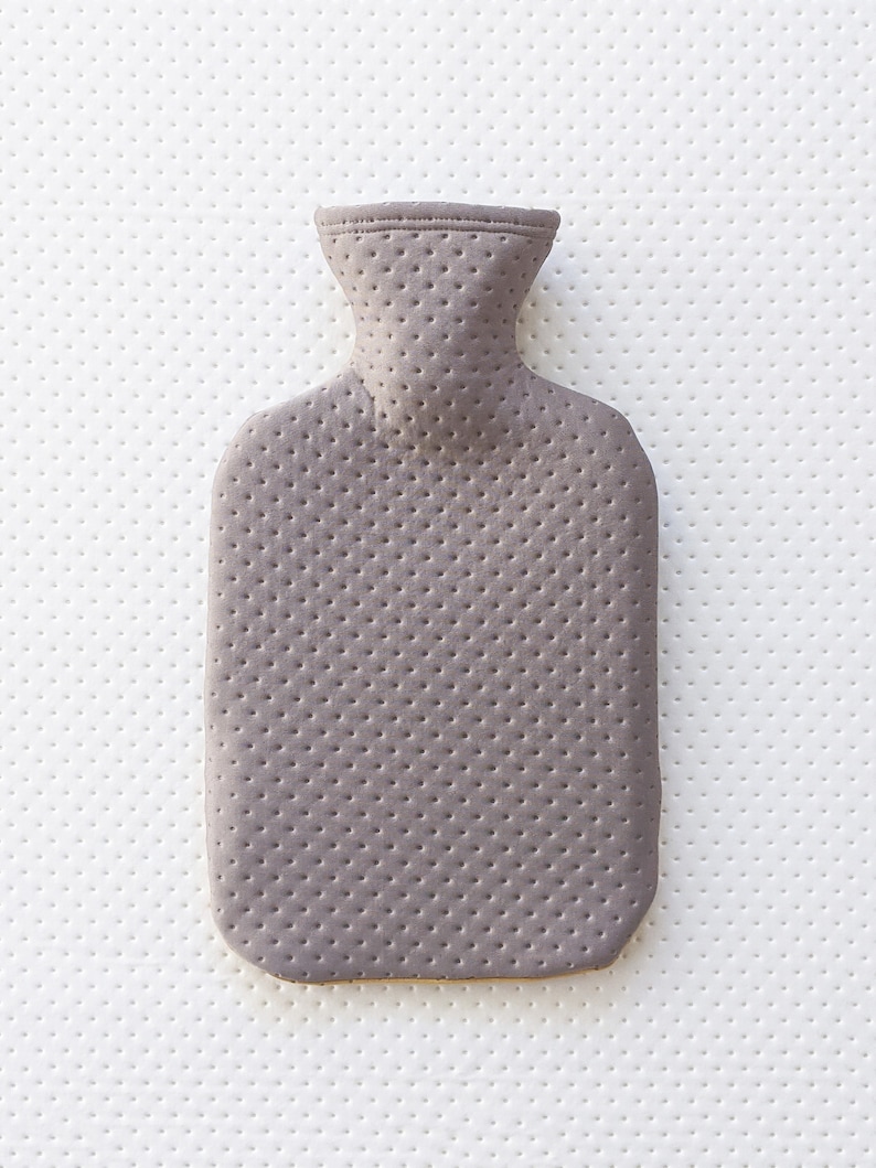 Puede incluir: Una botella de agua caliente gris con una superficie texturizada. La botella tiene un cuello estrecho y un cuerpo redondeado.