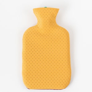 May include: A yellow rubber hot water bottle with a textured surface. The bottle has a narrow neck and a rounded body.