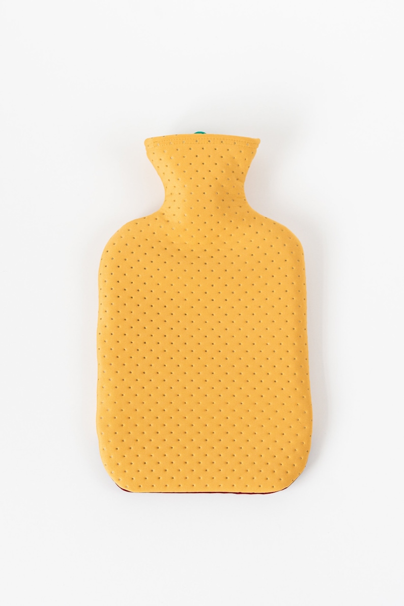 May include: A yellow rubber hot water bottle with a textured surface. The bottle has a narrow neck and a rounded body.