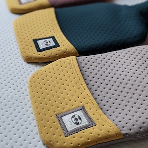 Puede incluir: Tres botellas de agua caliente con cubiertas de diferentes colores. Las cubiertas est&aacute;n hechas de un material suave y texturizado con un peque&ntilde;o logotipo en la parte delantera. El logotipo es un c&iacute;rculo con un perezoso dentro. Las botellas de agua caliente est&aacute;n apiladas una encima de la otra.