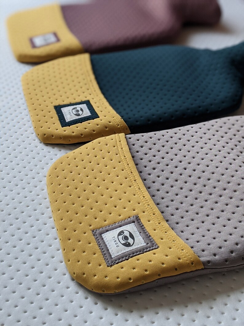 Puede incluir: Tres botellas de agua caliente con cubiertas de diferentes colores. Las cubiertas est&aacute;n hechas de un material suave y texturizado con un peque&ntilde;o logotipo en la parte delantera. El logotipo es un c&iacute;rculo con un perezoso dentro. Las botellas de agua caliente est&aacute;n apiladas una encima de la otra.