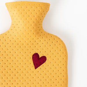 May include: A yellow rubber hot water bottle with a red heart on the front.