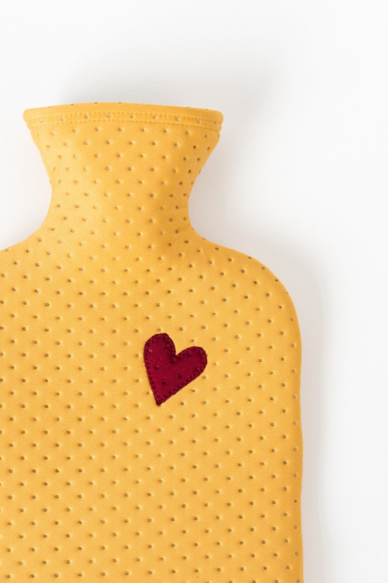 May include: A yellow rubber hot water bottle with a red heart on the front.