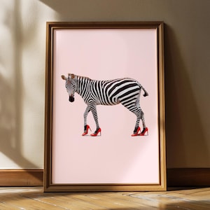 Könnte beinhalten: Gerahmter Kunstdruck mit einem Zebra mit schwarz-weißen Streifen, das leuchtend rote High-Heels trägt. Das Zebra ist vor einem zartrosa Hintergrund platziert. Der Rahmen hat einen warmen, natürlichen Holzton.