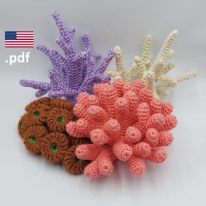 以下が含まれることがあります： 紫、白、ピンク、茶色の4つの異なる色の編み物で作られたサンゴ礁のピース。サンゴのピースは糸で作られており、質感があり、リアルな外観をしています。