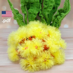 May include: A crochet pattern document labeled .pdf with a US flag icon, featuring a cluster of bright yellow fuzzy flowers with orange centers and long, textured green leaves. The design showcases intricate yarn work and vibrant colors.