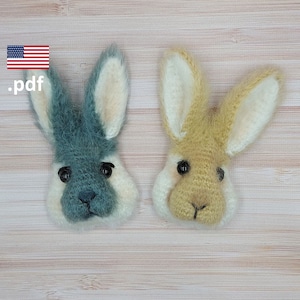 May include: Two crocheted bunny rabbit faces, one is light blue and white, the other is light brown and white. Both have black eyes and a black nose.