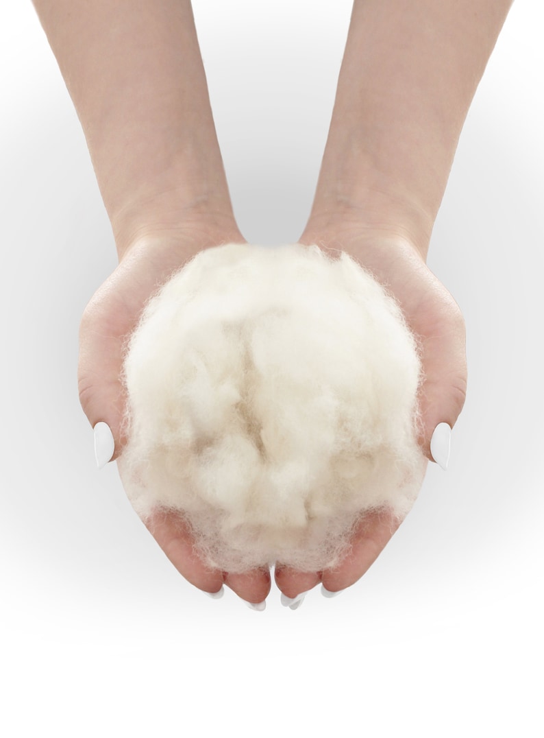 May include: A close-up of a person's hands holding a large, fluffy ball of white wool.