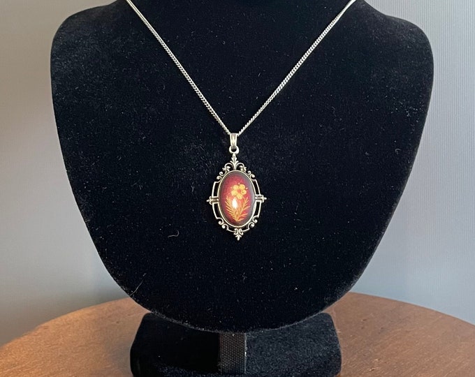 Antique and rare metal and resin pendant decorated with a yellow flower on a red background