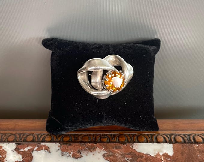 Antique and rare brooch in silver-plated metal and an amber stone (citrine, topaz or glass) in the shape of an intertwined ribbon
