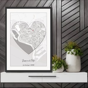 May include: A black and white map of a city in the shape of a heart with a red dot marking a location. The text "Suzanne & Peter" and "We fell in love..." is below the map.