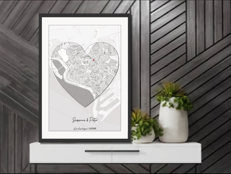 May include: A black and white map of a city in the shape of a heart with a red dot marking a location. The text "Suzanne & Peter" and "We fell in love..." is below the map.