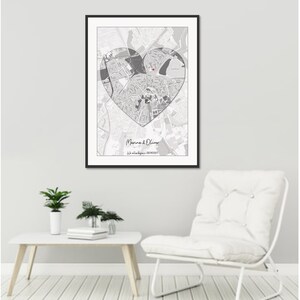 May include: A black framed print with a gray and white map of a city in the shape of a heart. The text "Marina & Oliver" and "Our love story began - 08/08/2017" is printed below the map.