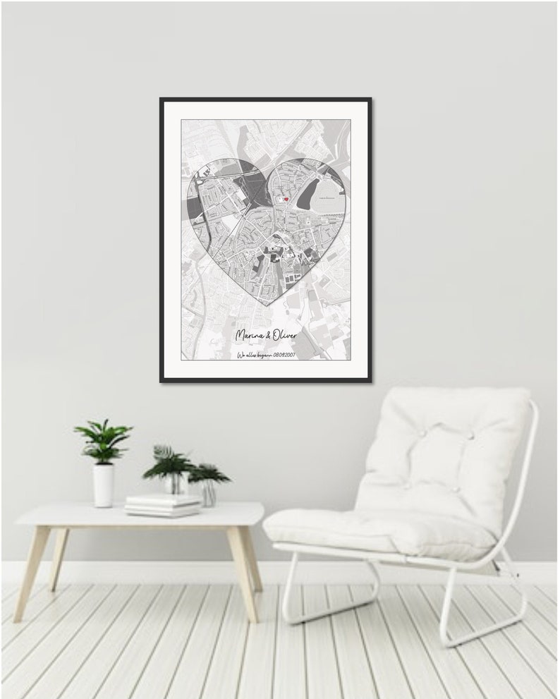 May include: A black framed print with a gray and white map of a city in the shape of a heart. The text "Marina & Oliver" and "Our love story began - 08/08/2017" is printed below the map.