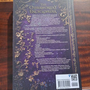 May include: The Otherworldly Encyclopedia book, volume DEF, with a dark purple cover and gold floral accents. The back cover features text about witchcraft topics, rituals, and spells. ISBN 9798282858921.