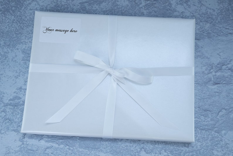 May include: A white gift box with a white ribbon tied in a bow. A small white label on the box says "Your message here".