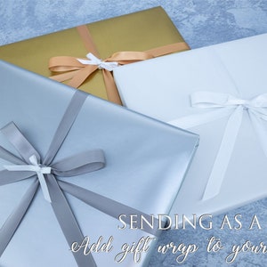 May include: Three gift boxes wrapped in different colors: silver, gold, and white. Each box is tied with a ribbon and bow. The text "SENDING AS A GIFT? Add gift wrap to your order" is at the bottom of the image.