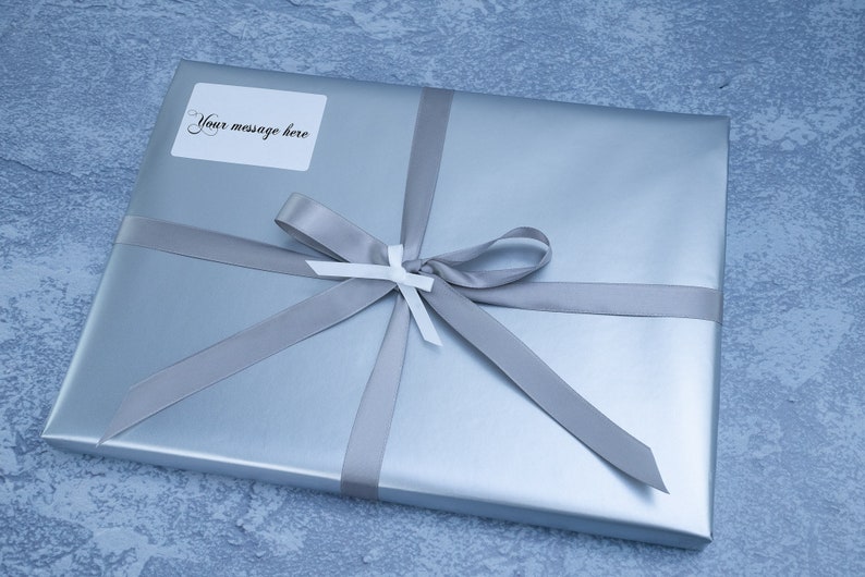 May include: A silver gift box with a gray ribbon and bow. A white label with the text "Your message here" is attached to the box.