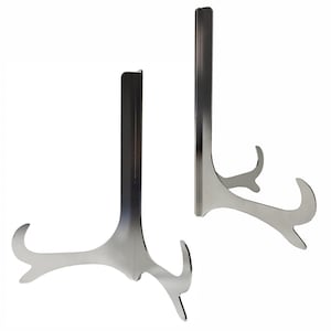 May include: Two silver-colored metal display stands. Each stand has a tall, vertical support with a curved base and a lip at the top to hold a plate or other item. The stands are designed to hold items upright for display.